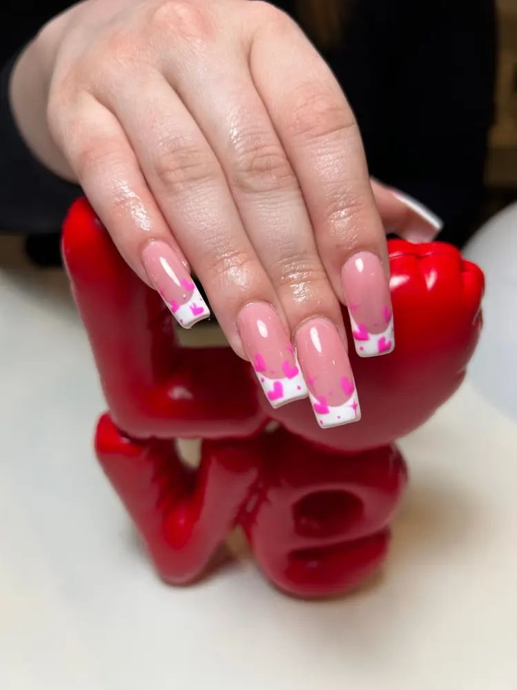 Pink almond nails with white and pink french tips, held up against a red sculpture